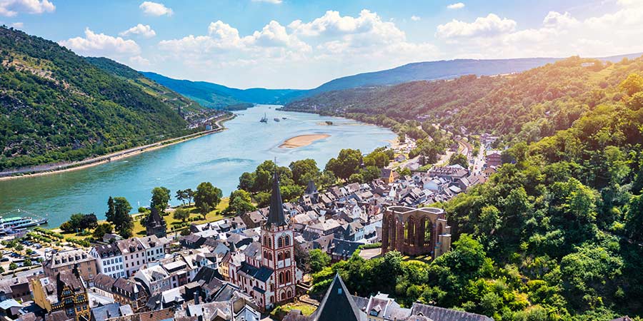 The Rhine river can be seen in the distance, surrounded by lush greenery and traditional german architecture.  